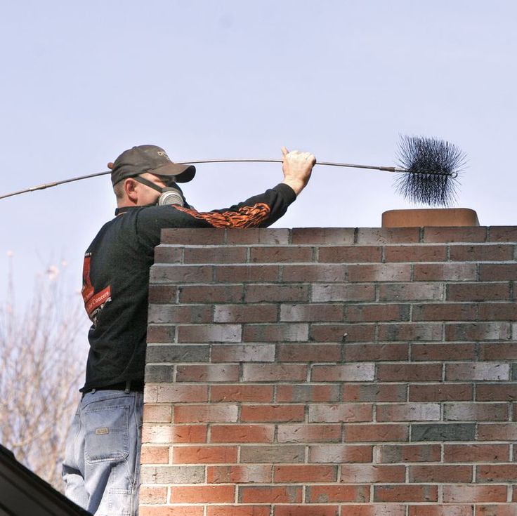 Rooftop chimney sweep brushing a flue